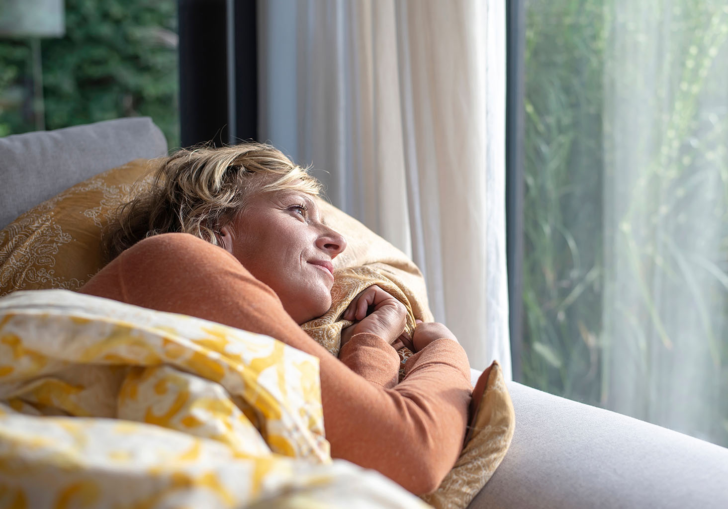 woman in her bed looking into window