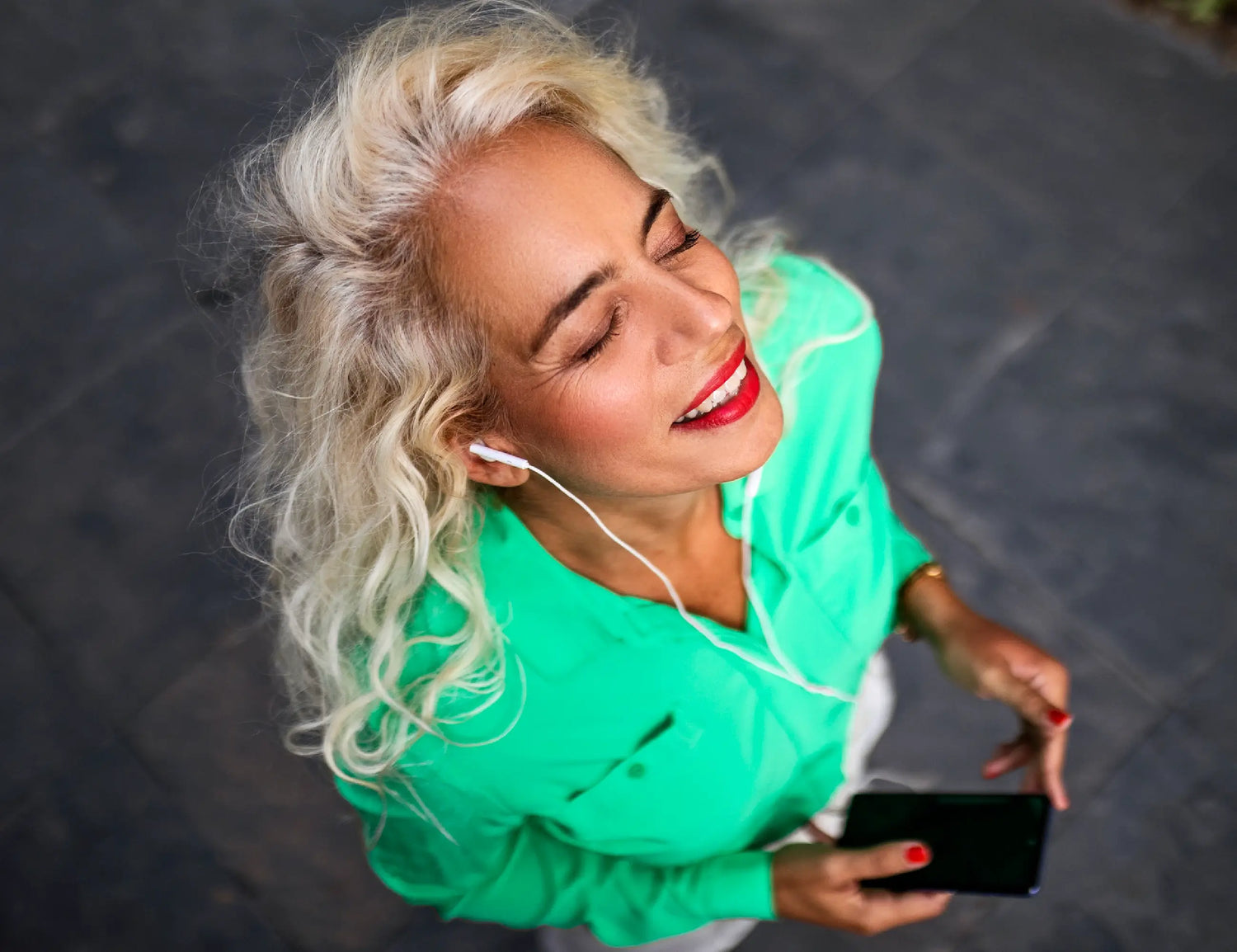 aerial view of a blonde lady in a green shirt listening to music