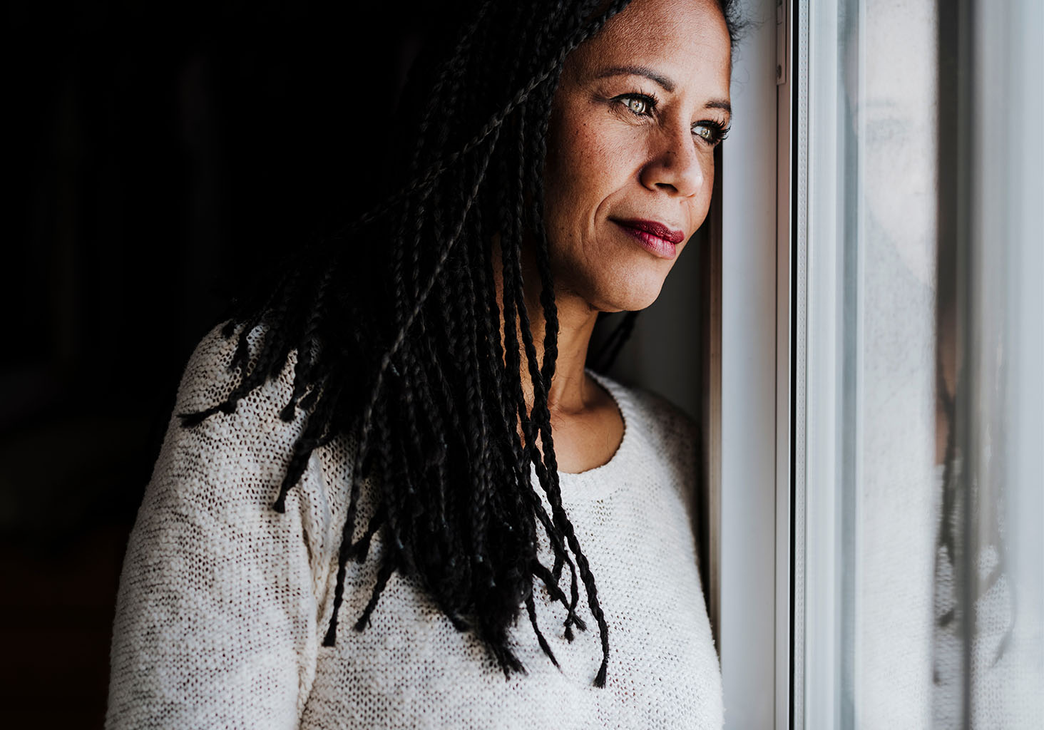 african american woman looking outside through a window